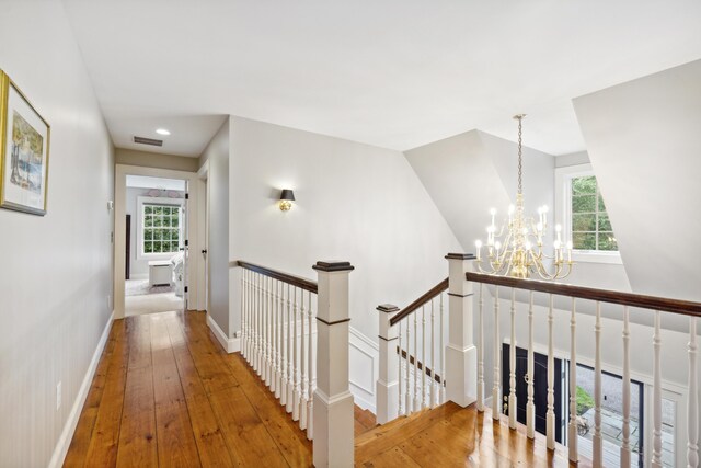 corridor featuring hardwood / wood-style flooring, a notable chandelier, and a wealth of natural light