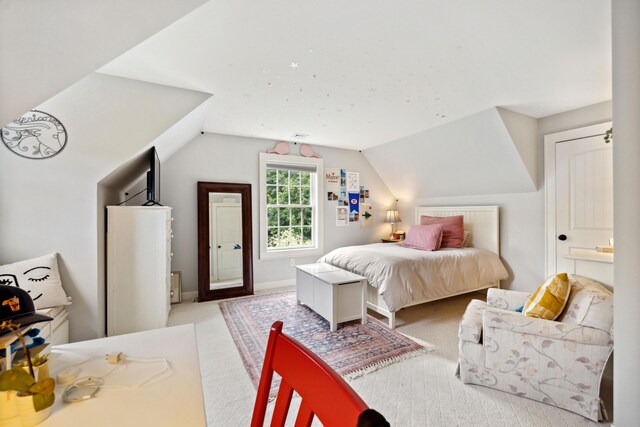 bedroom with lofted ceiling, light colored carpet, and connected bathroom