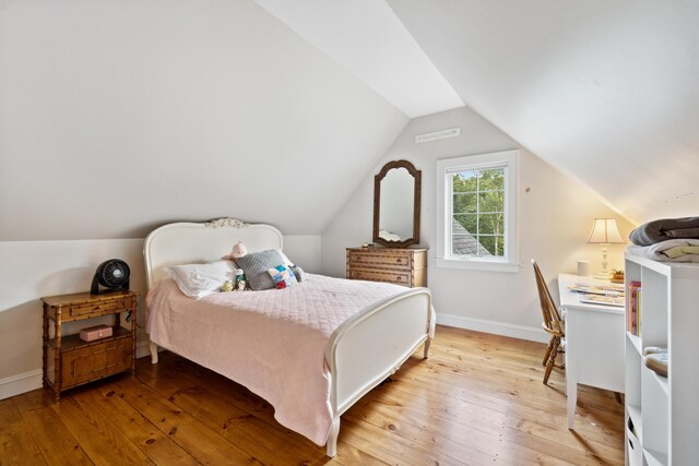 bedroom with vaulted ceiling and light wood-type flooring