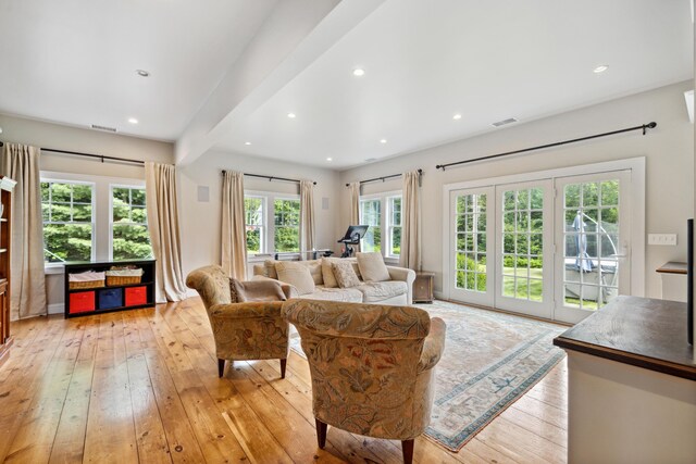 living room with beamed ceiling, light hardwood / wood-style flooring, and french doors