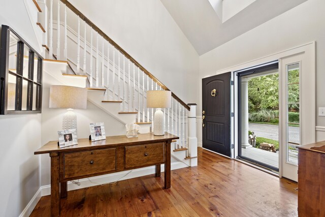 foyer entrance with hardwood / wood-style floors and high vaulted ceiling