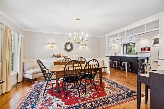 dining room with a chandelier, crown molding, and light wood-type flooring