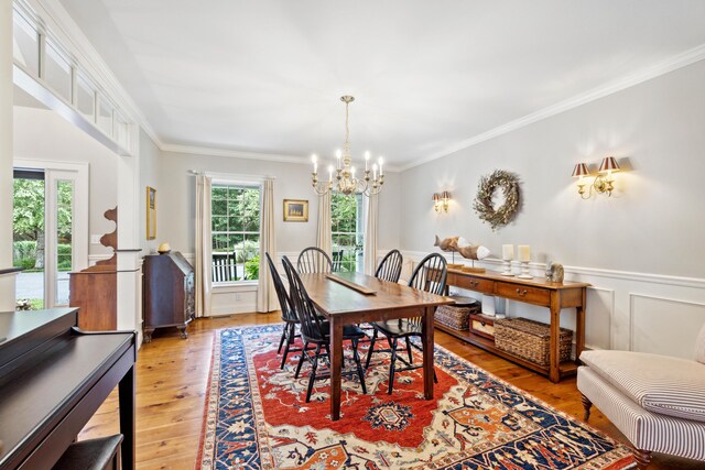 dining space featuring plenty of natural light, an inviting chandelier, wood-type flooring, and ornamental molding