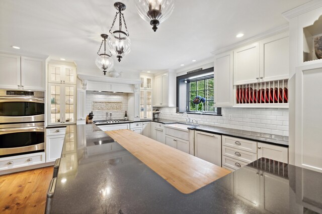 kitchen with white cabinets, stainless steel appliances, tasteful backsplash, and pendant lighting