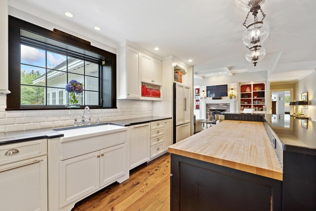 kitchen with decorative light fixtures, butcher block counters, decorative backsplash, light wood-type flooring, and white cabinetry