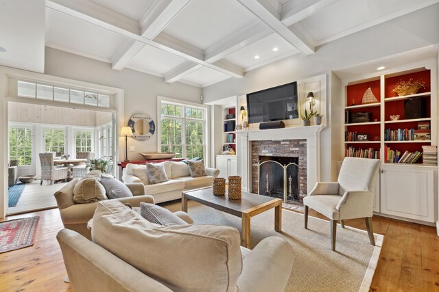 living room featuring beamed ceiling, light hardwood / wood-style floors, a brick fireplace, and coffered ceiling