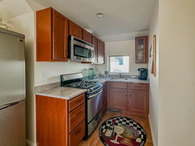 30 Ocean Ave, Kennebunkport, ME 04046 - kitchen featuring stainless steel appliances, a sink, light wood-style flooring, glass insert cabinets, and brown cabinets