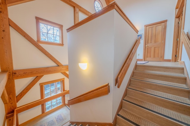 stairs featuring beamed ceiling and high vaulted ceiling