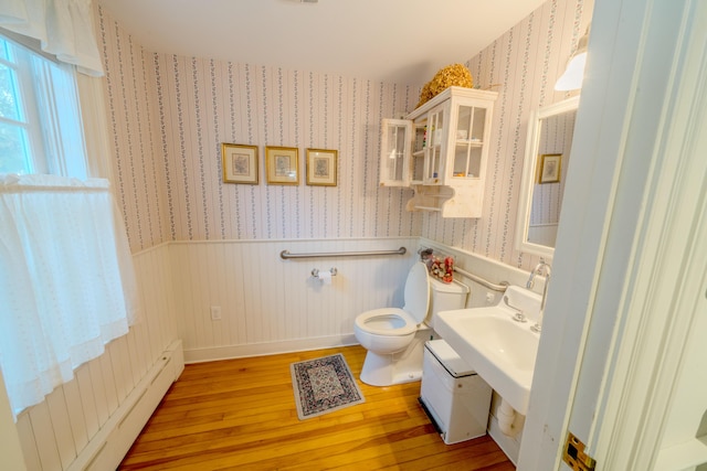 bathroom with hardwood / wood-style floors, toilet, and baseboard heating