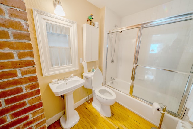 bathroom featuring hardwood / wood-style flooring, toilet, and bath / shower combo with glass door