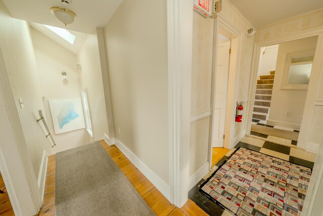 hallway featuring light wood-type flooring and a skylight