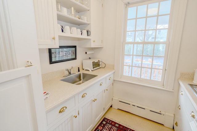 kitchen with white cabinets, a baseboard heating unit, and sink