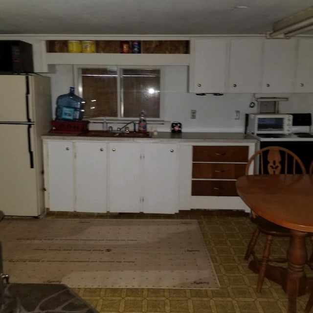 kitchen featuring white refrigerator, white cabinets, and sink