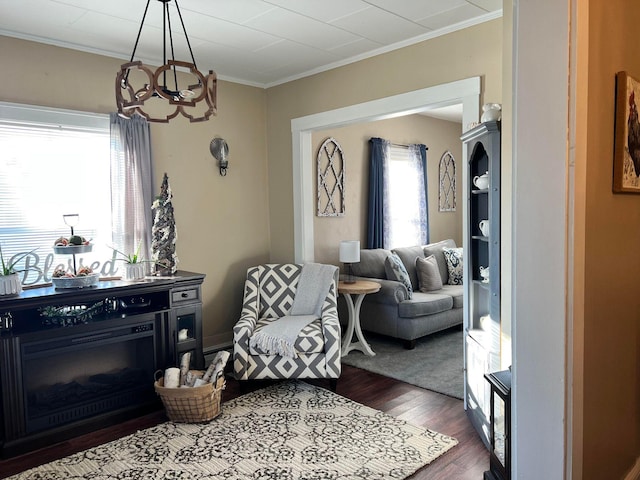 living room featuring dark hardwood / wood-style floors, an inviting chandelier, and ornamental molding