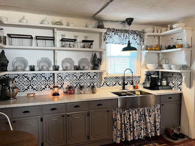 kitchen with decorative light fixtures, sink, gray cabinetry, and a textured ceiling