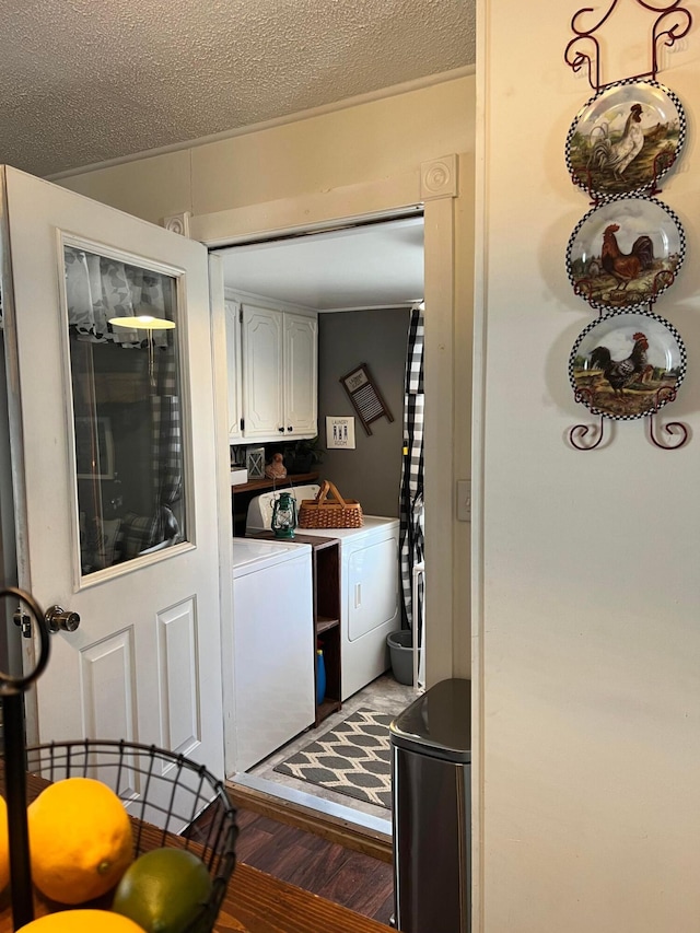 clothes washing area with a textured ceiling, cabinets, washer and clothes dryer, and wood-type flooring