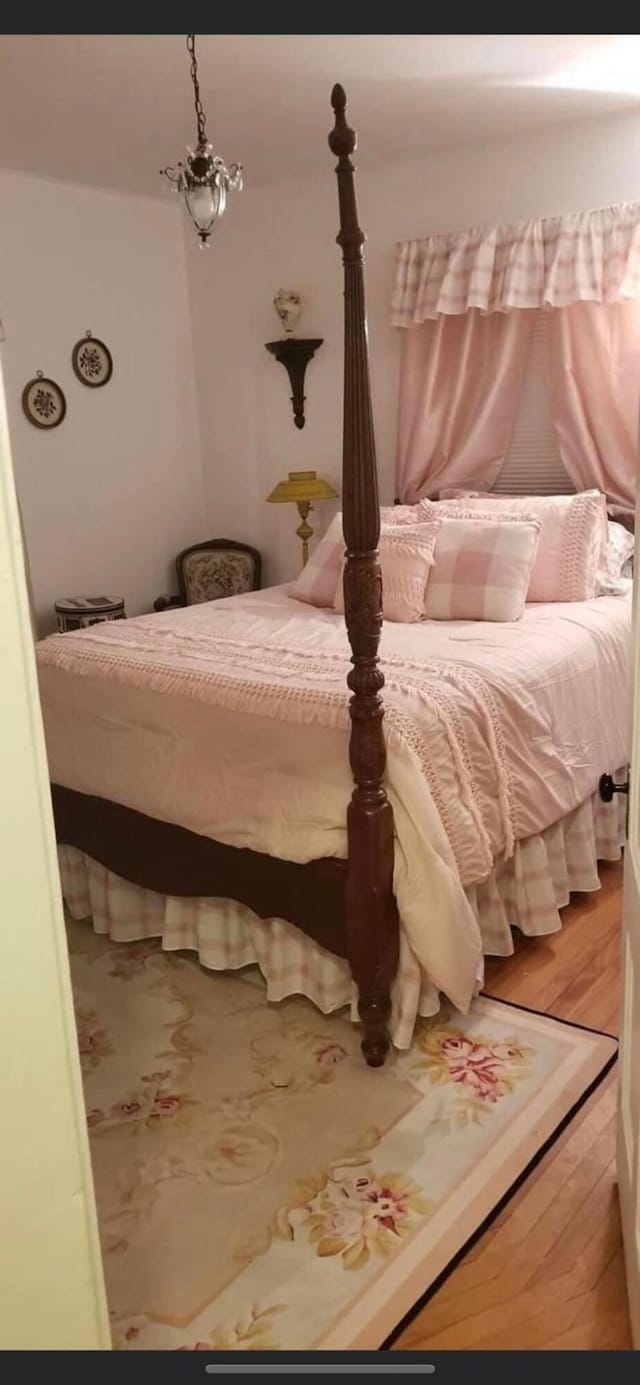 bedroom with wood-type flooring and a notable chandelier