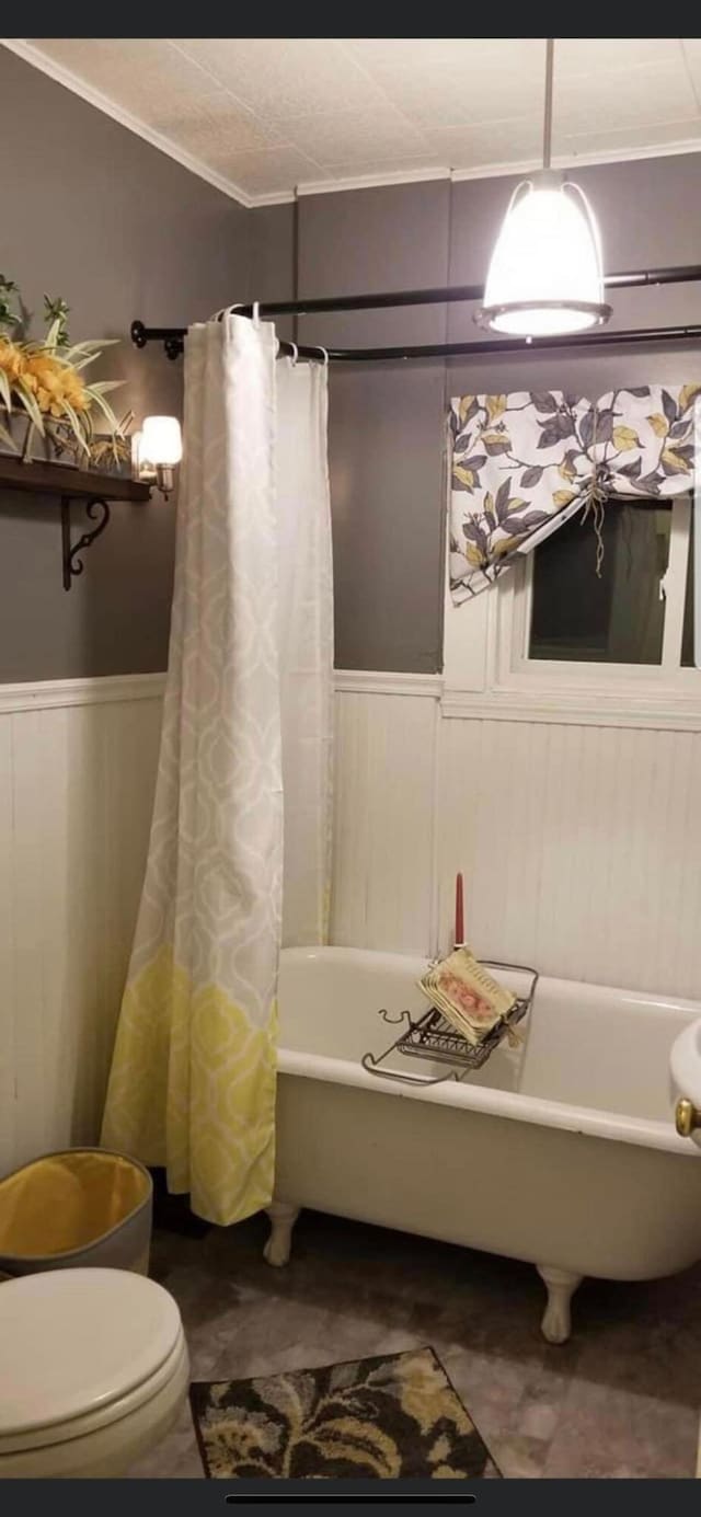 bathroom with toilet, wood walls, shower / bath combo with shower curtain, and ornamental molding