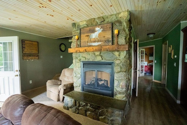 living area with hardwood / wood-style flooring, a stone fireplace, and wood ceiling