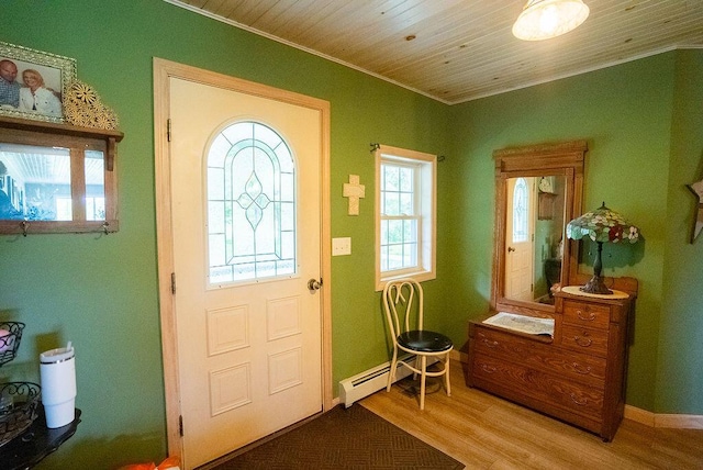 foyer entrance with hardwood / wood-style floors, ornamental molding, and baseboard heating