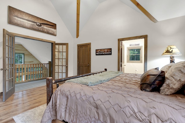 bedroom featuring beamed ceiling, light hardwood / wood-style flooring, french doors, and high vaulted ceiling