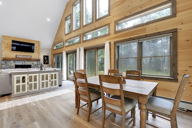 dining space featuring light hardwood / wood-style floors, a fireplace, plenty of natural light, and high vaulted ceiling