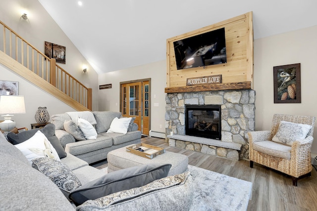 living room featuring high vaulted ceiling, wood-type flooring, a baseboard heating unit, and a stone fireplace