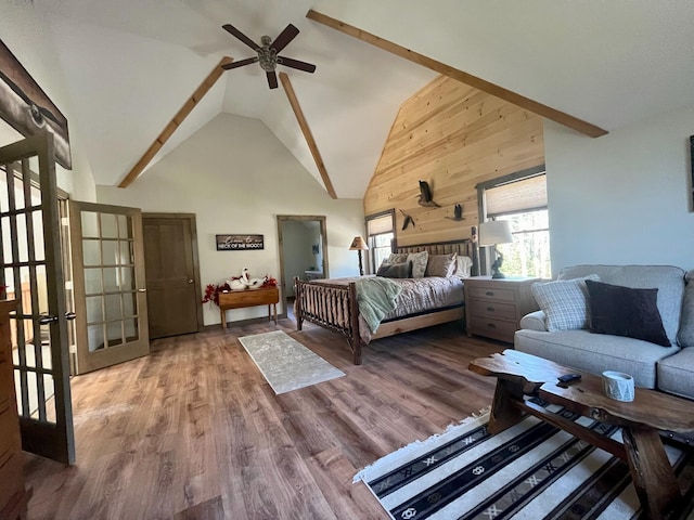 bedroom with hardwood / wood-style flooring, wooden walls, ceiling fan, french doors, and high vaulted ceiling