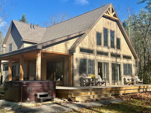 back of property with a deck and a hot tub