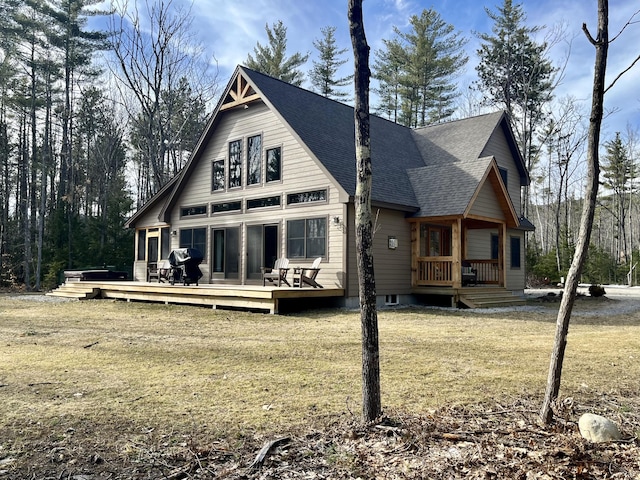 rear view of property with a yard, a wooden deck, and roof with shingles
