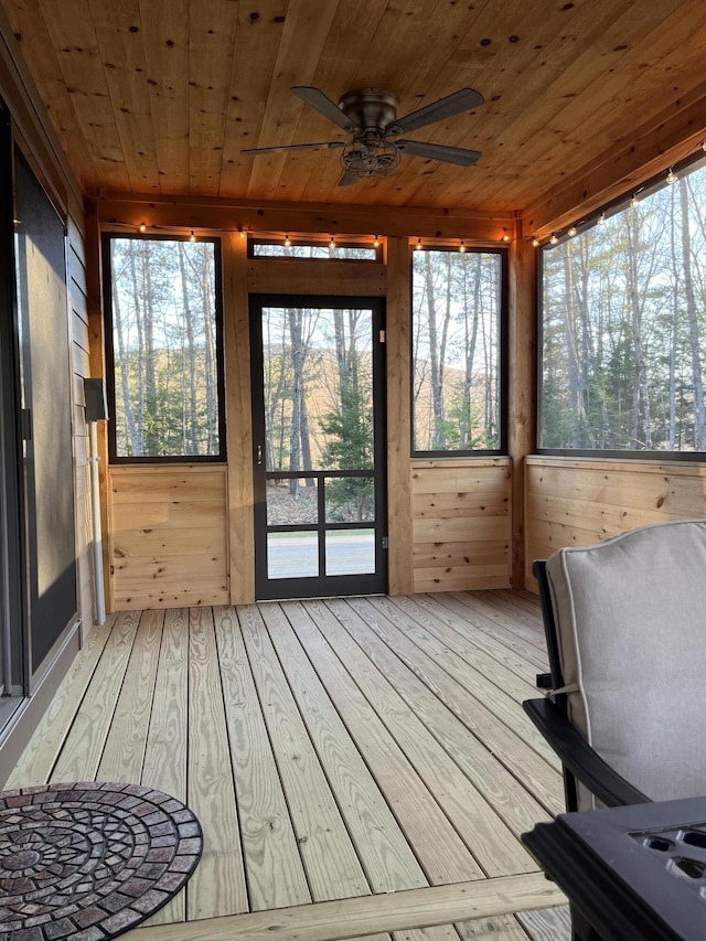 sunroom featuring wood walls, a ceiling fan, wooden ceiling, a wealth of natural light, and hardwood / wood-style flooring