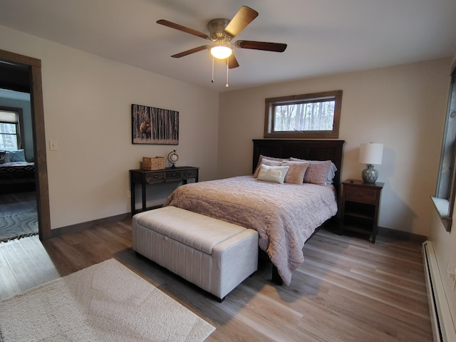 bedroom with ceiling fan, baseboards, a baseboard heating unit, and wood finished floors