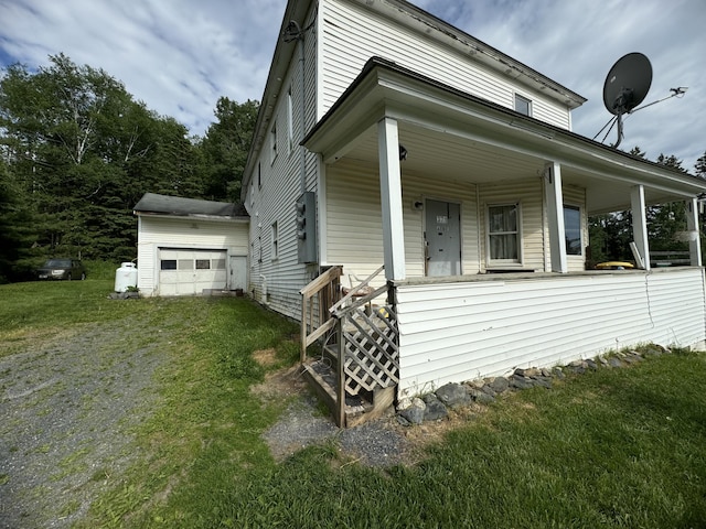 view of property exterior with an outbuilding, a yard, covered porch, and a garage