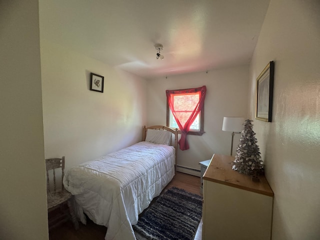 bedroom featuring a baseboard heating unit and hardwood / wood-style floors