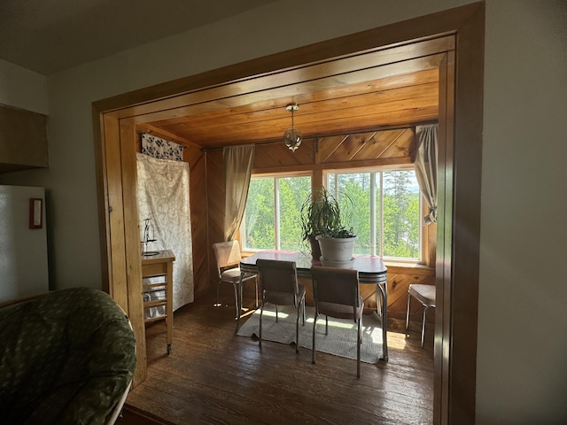 dining area with dark wood-type flooring and wooden walls