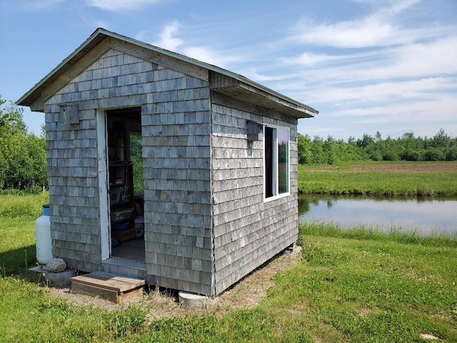 view of outbuilding with a water view and a lawn