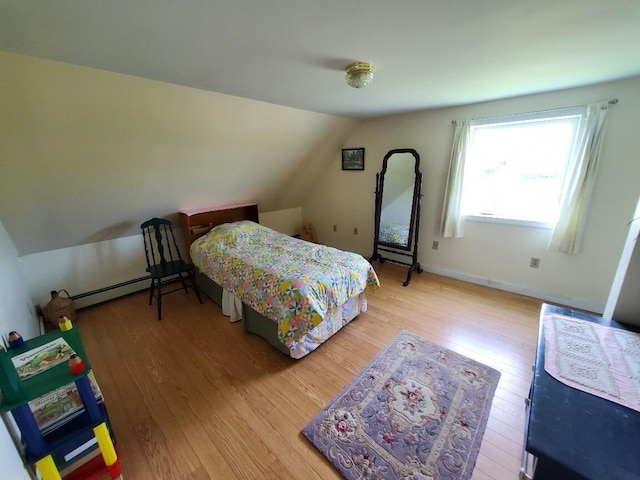 bedroom with hardwood / wood-style floors, a baseboard radiator, and vaulted ceiling