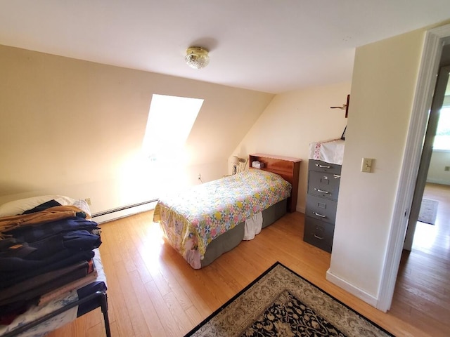 bedroom featuring light wood-type flooring, a skylight, and baseboard heating