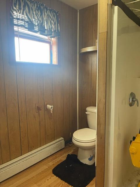 bathroom with wood walls, a baseboard radiator, and hardwood / wood-style flooring