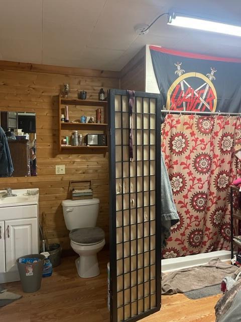 bathroom with wooden walls, vanity, wood-type flooring, and toilet