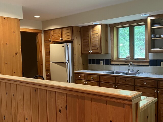 937 N Rd, Bethel, ME 04217 - kitchen with freestanding refrigerator, tile countertops, brown cabinetry, recessed lighting, and backsplash