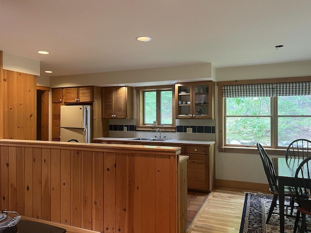 kitchen featuring white refrigerator, a healthy amount of sunlight, light hardwood / wood-style flooring, and tasteful backsplash