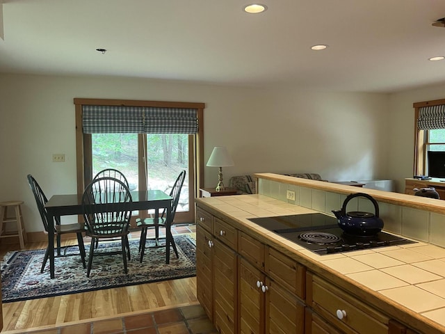 kitchen with tile countertops, black electric cooktop, and hardwood / wood-style floors