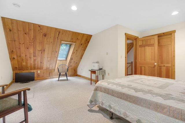 bedroom with carpet flooring, wood walls, lofted ceiling with skylight, and a closet