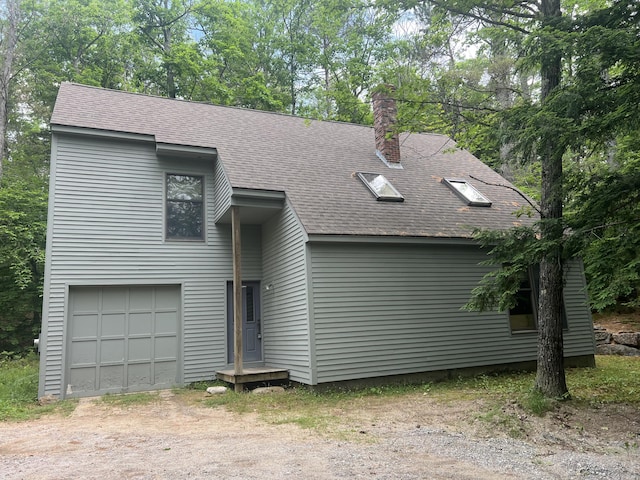 937 N Rd, Bethel, ME 04217 - view of front facade featuring a shingled roof, dirt driveway, an attached garage, a chimney, and view of wooded area