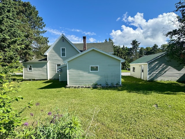 rear view of house featuring a lawn and an outdoor structure