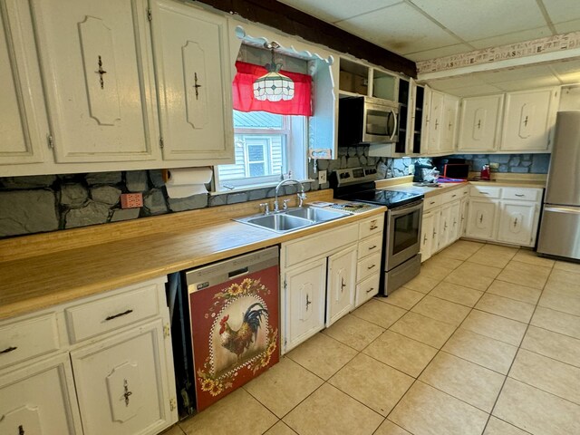 kitchen featuring light tile patterned floors, stainless steel appliances, decorative light fixtures, and sink