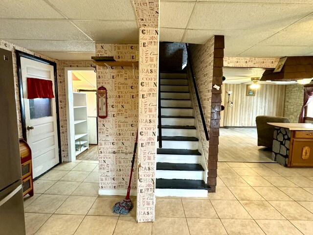 stairway featuring ceiling fan, a paneled ceiling, and tile patterned floors