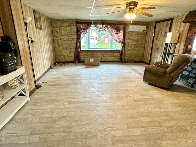 sitting room with ceiling fan, a paneled ceiling, wood walls, and an AC wall unit