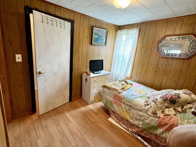 bedroom featuring light wood-type flooring and wooden walls